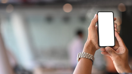 Man's hands holding mobile phone in meeting room.