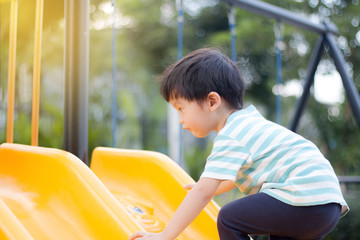 Young asian boy playing on a blue playground slide
