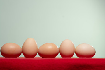 Whole eggs with set in a row on red background.