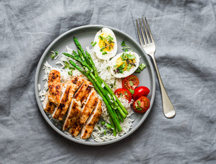 Healthy lunch - rice, asparagus, grilled chicken, boiled egg on a grey background, top view