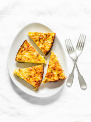 Slice of leeks, potatoes, zucchini tortilla on a light background, top view. Delicious appetizer, tapas, breakfast