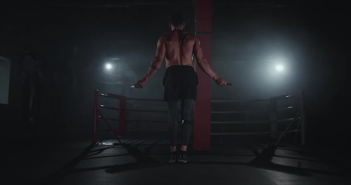 Awesome bodybuilding guy jumping on the rope in a cross fitness class he concentrated doing his hard workout training