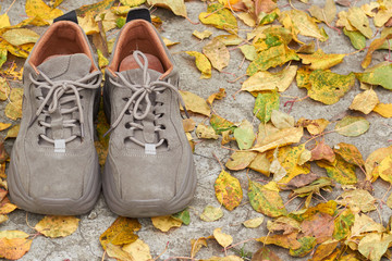 Sadness mood with the arrival of autumn, shoes on the background of fallen leaves. The concept of the arrival of autumn.
