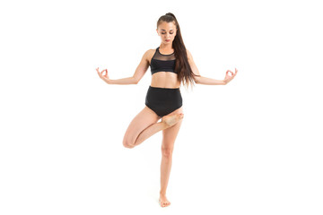 girl is concentrated on yoga in a black sports swimsuit on a white background