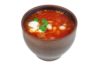 Clay bowl with traditional Ukrainian borscht (beet root soup) isolated on white background.