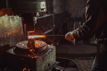 caucasian young strong blacksmith working with open fire in furnace. The blacksmith forging hot...