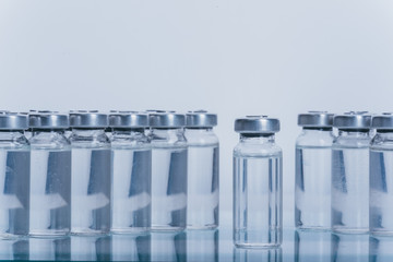 Glass medical ampoule vial for injection. Medicine is dry white drug penicillin powder or liquid with of aqueous solution in ampulla. Close up. Bottles ampule with aluminum cap on backgrounds gray.