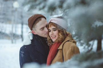 Romantic stylish couple embracing in winter park. Dating, peeple and seasonal concept.