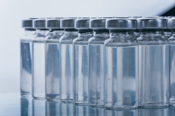 Glass medical ampoule vial for injection. Medicine is dry white drug penicillin powder or liquid with of aqueous solution in ampulla. Close up. Bottles ampule with aluminum cap on backgrounds gray.