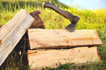 firewood, a sharp ax sticks out in a log, nature green grass and river, sunny day