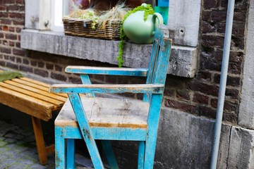 View on isolated old retro wooden chair with flaking paint and windowsill in front of house brick wall