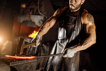 Fototapeta premium serious brutal blacksmith makes metal for future manufacturing isolated in workshop