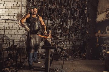 Fototapeta na wymiar young blacksmith heating hot red metal for future manufacturing in workshop. forging industry