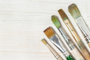 Five painting brushes wood background