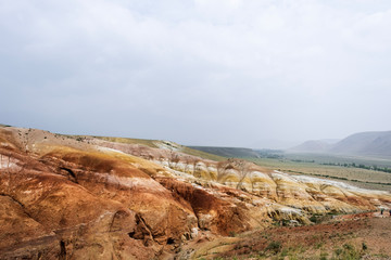 Landscape of an unusual place. Layers of clay, lime, sand. Mars mountains. The color of iron, red shades of the earth. Unusual terrain. Mountain Altai. Tourist trip.