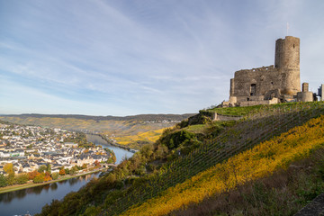 Fototapeta premium View at Landshut castle in Bernkastel-Kues on the river Moselle in autumn with multi colored vineyards