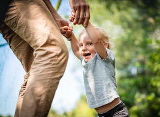 Little child with his dad playing on trampoline outdoor in backyard
