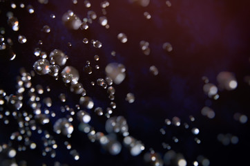 Abstract bokeh pattern of sparkling glass droplets on a dark blue background