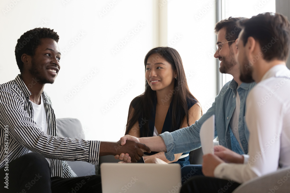 Sticker multiethnic partners sitting on couch shake hands start group meeting