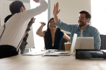 Multi-ethnic businesspeople giving high five celebrating closing profitable deal