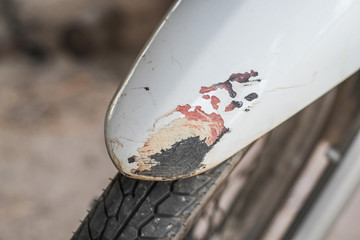 White motorcycle fender peeling off from scratching.
