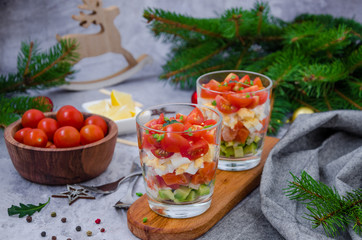  Portion salad with smoked salmon, avocado, egg, cherry tomatoes with cream cheese dressing in a glass. Holiday salad for Christmas and New Year.