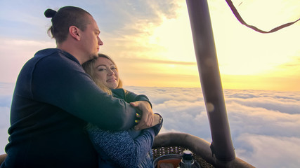 Adventure love couple on hot air balloon watermelon. Man and woman kiss hug love each other. Burner directing flame into envelope. Fly in morning blue sky. Happy people take selfie in hot air ballon.