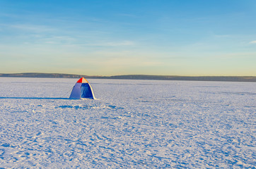 Fisherman tent on the ice of a frozen lake on a Sunny day.