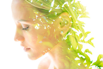 Double exposure close up profile portrait of a young pretty woman interwoven with bright leaves of...