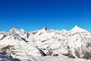 Fototapeta na wymiar Alpine landscape full of snowy mountains, and cloudless blue sky.