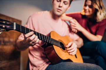 two friends sit playing the guitar, relax and enjoy performing music, using acoustic guitar instrument