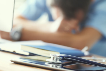 Tired man doctor sleeps lying on his hands while sitting at a computer desk. Doctor works on a computer in the clinic after a night shift.