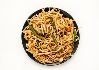 Asian vegetarian food udon noodles with Beijing cabbage, carrots, green beans, sweet pepper, onions on a plate on a white background