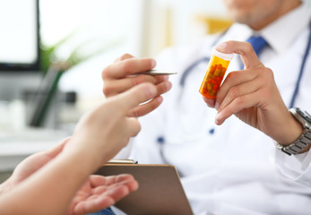 Close-up of doctor's hand holding medicine and giving it to his patient.