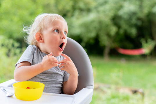 Surprised baby child looking at something while eating outdoor