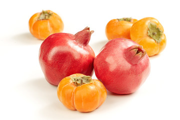 two ripe bright red pomegranates and persimmon