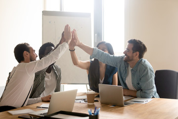 Multiethnic work team give high five motivated for shared success