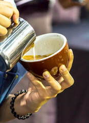 Showcase Barista making Latte art coffee and Barista pouring fresh milk create art pattern on Latte coffee at cafe.