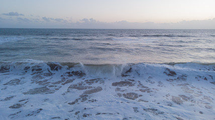 An aerial view of crashing waves at dawn