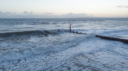 An aerial view of crashing waves on a groyne (breakwater) at dawn