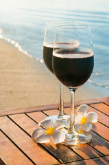 Romantic outdoor scene: two glasses of red wine on beach