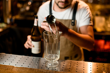 Bartender pours cocktail with stainless steel jigger