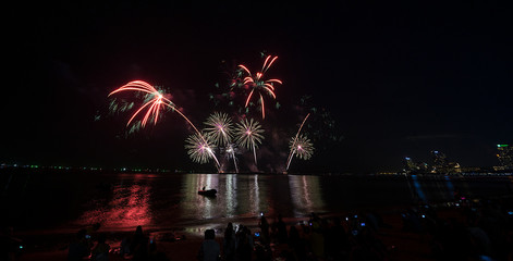 Colorful fireworks display over city on the beach. Firework celebration sparkling in midnight sky, 
