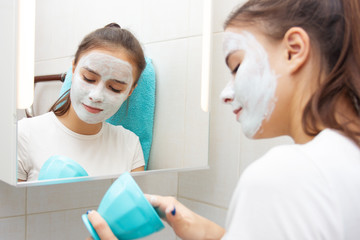 Health and beauty. Facial skin care. Young girl makes a moisturizing cleansing face mask