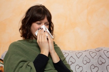 Girl on the sofa while sneezing