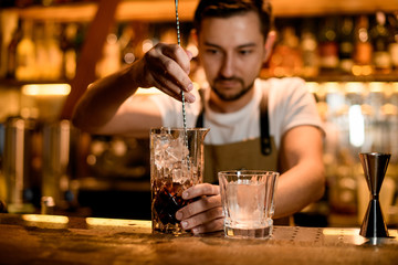 Bartender stirs alcohol with ice in glass