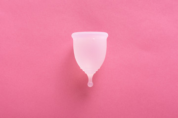 Close up shot of menstrual cup isolated over pink background. Studio picture of modern sanitary products for period. Women health concept, gynecology, hygiene, zero waste alternatives concept.