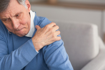 Senior Gentleman Having Shoulder Pain Sitting On Couch