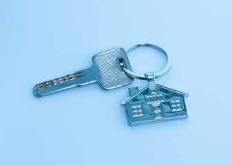 key chain with house symbol and keys on blue background,Real estate concept
