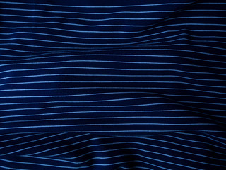 Dark blue striped crumpled fabric abstract background.
